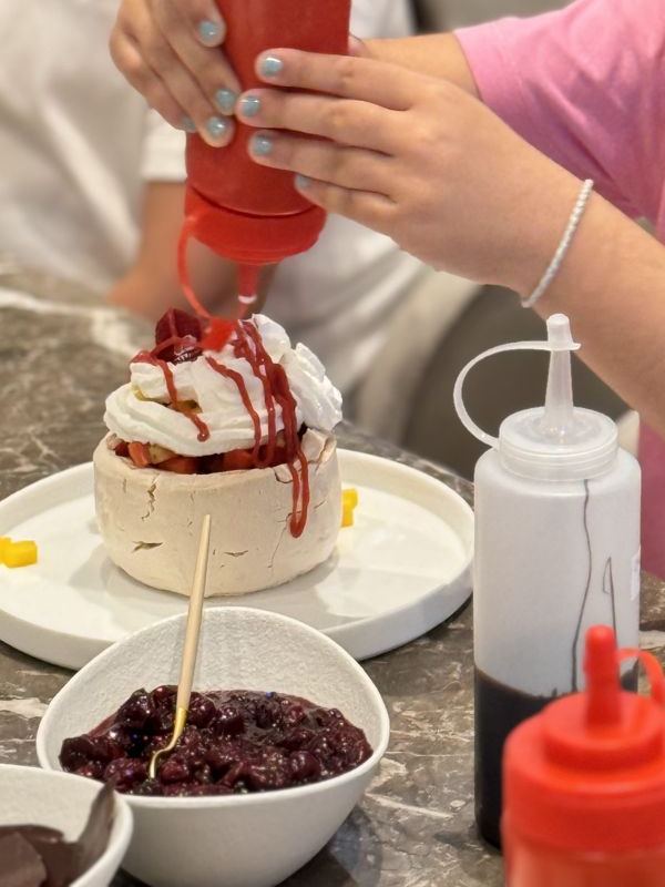 Guest adding sauce to her pavlova