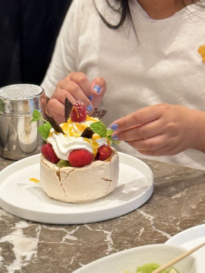 Guest finishing a pavlova with fruit